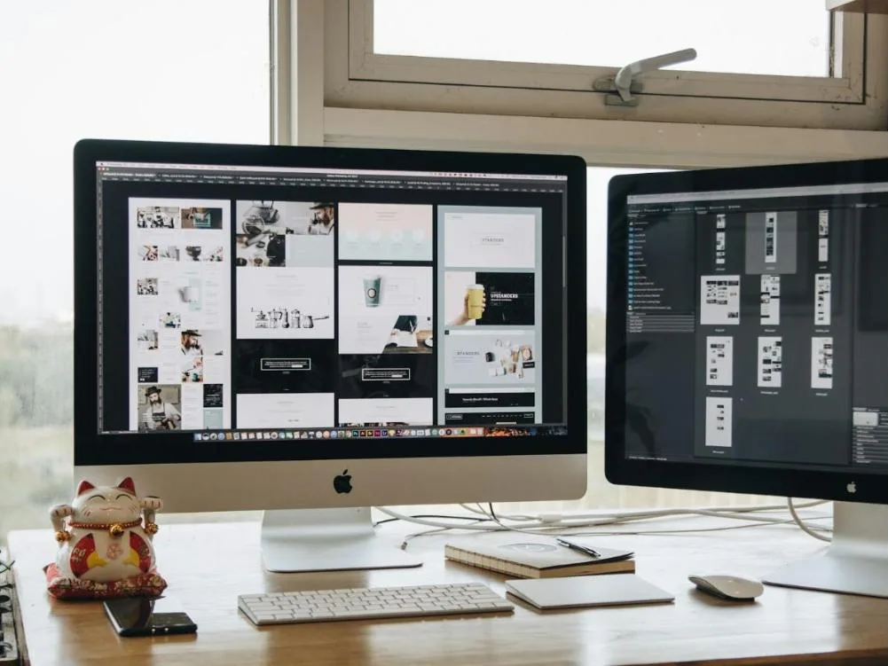 Postazione di web design con le pagine di un sito su due monitor
